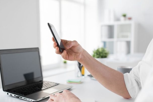 a black laptop and a hand holding a mobile phone in an office for copywriting and content creation services and website copywriting